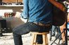 A man playing an acoustic guitar with a Vagabond leather strap by Zilker Belts.