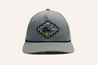 A grey Zilker Sessions Imperial Hat by Zilker Belts with a circular patch on the front featuring a stylized design with a bull and text, perfect for fans of the SlackerTide live music series.