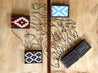 Four Bouldin Creek Wallets by Zilker Belts, featuring Argentine woven fabric and various geometric patterns, are displayed on a map-themed background with two on the left and two on the right.