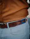 A man is wearing a Kite Fest belt by Zilker Belts, with a pattern on it.