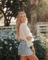 A blonde woman in a denim skirt posing for a photo while wearing Zilker Belts' Native belt.