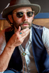 A man wearing a Zilker Bolo Tie, Zilker hat, vest and sunglasses.