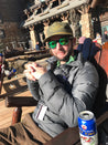 a man sitting in a wooden chair with a Zilker Belts Greenbelt Rope Hat on his head and a beer in his hand.