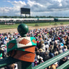 A crowd of people watching the Save Muny horse race sponsored by Zilker Belts.