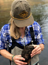 A woman wearing a Greenbelt Rope Hat by Zilker Belts, holding a rock.