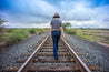 A woman is walking on a train track in the desert wearing Zilker Belts' Native.